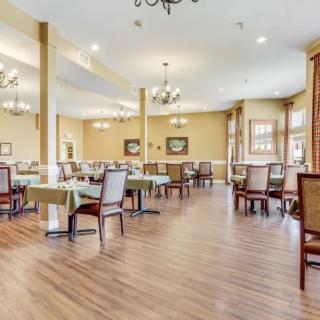 An elegant dining room featuring hardwood floors, neatly arranged tables and chairs, and decorative chandeliers.