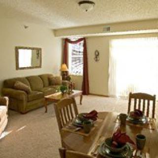 A cozy living and dining area with a sofa, table, and chairs, featuring warm decor.