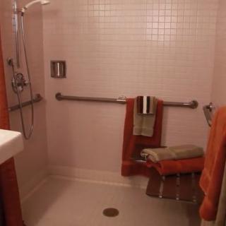 An accessible bathroom with a shower, grab bars, and a folding seat.