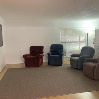 A cozy living area featuring several recliner chairs arranged on a carpeted floor.