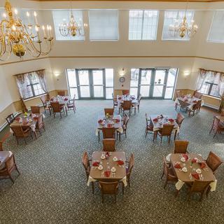 A spacious and elegant dining area with neatly arranged tables, chairs, and chandeliers.