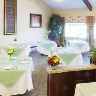 A cozy and well-decorated dining area with tables set for guests, featuring floral centerpieces.