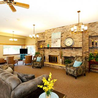 A cozy and inviting living room with a rustic brick fireplace, comfortable seating, and bright floral accents.