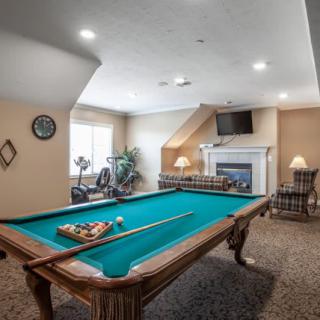 A cozy billiard room featuring a pool table, fireplace, and wall-mounted TV.