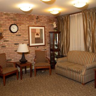 A cozy living room setting with a brick wall, comfortable seating, and warm lighting.