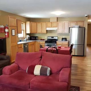 An open floor plan combining a living room and kitchen, featuring a red sofa, wooden cabinets, and modern appliances.