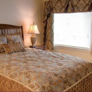 A cozy bedroom with a patterned bedspread and matching curtains.
