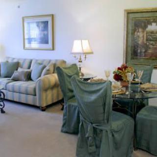 A cozy living room with a sofa and dining area, featuring elegant decor and artwork.