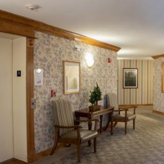 A cozy hallway featuring an elevator, seating area, and decorative elements.