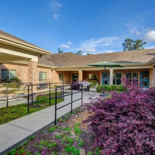 A charming building with a garden and walkway on a sunny day.