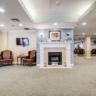 A cozy lobby area featuring a fireplace, armchairs, and a television.