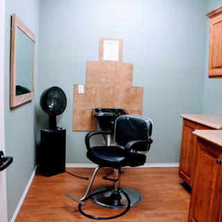 A cozy hair salon setup with a styling chair, mirror, and fan.