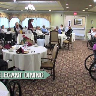 A spacious and elegant dining area where guests enjoy their meals, with several tables set and people seated, some in wheelchairs.
