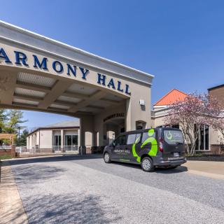 A vehicle parked in front of the entrance to Harmony Hall on a clear day.