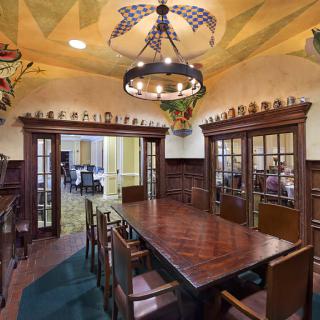 A traditional dining room featuring a large wooden table surrounded by chairs, with elegant decor and a chandelier overhead.