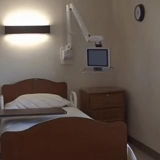 An empty hospital room with a bed and medical monitor.