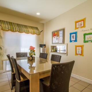 A cozy dining room with a modern table, surrounded by chairs and adorned with colorful artwork on the walls.