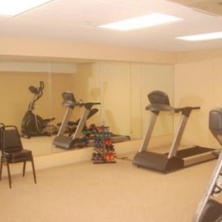 A small gym with exercise equipment including treadmills, an elliptical machine, and a set of dumbbells.