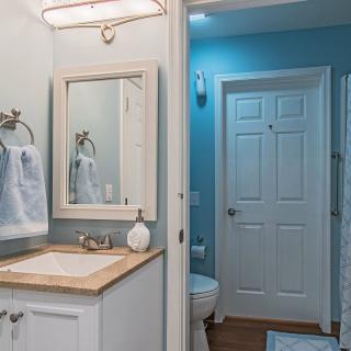 A modern bathroom with a sink, mirror, and blue walls.