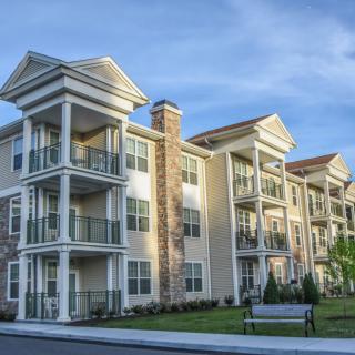A modern apartment building with multiple balconies under a clear blue sky.