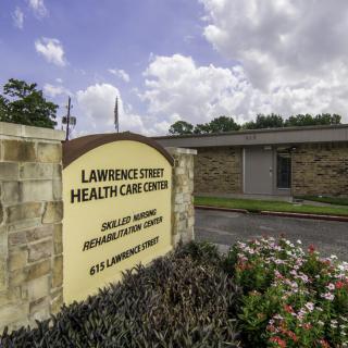 Entrance to a healthcare center with a sign and surrounding greenery.