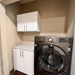 A modern laundry room with a washing machine and storage cabinets.
