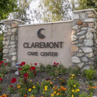 A stone sign for Claremont Care Center surrounded by colorful flowers.