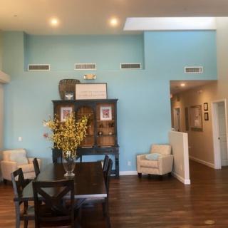 A modern living room with blue walls, featuring a dining table, chairs, and decorative elements.
