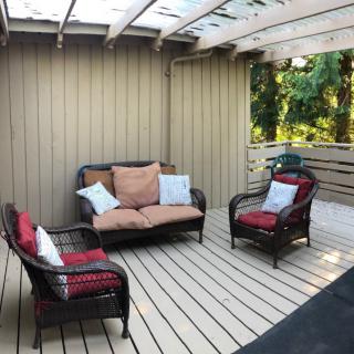 A cozy patio with wicker furniture and colorful cushions under a covered roof.