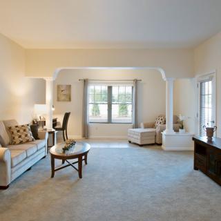 A spacious and elegantly designed living room with modern decor, featuring a comfortable sofa, a round coffee table, and large windows allowing natural light to fill the space.