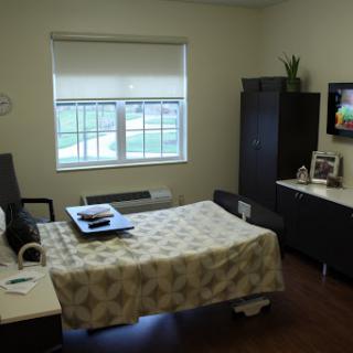 A well-lit and modern hospital room featuring a patient bed, a television, and a view outside the window.