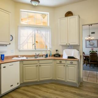 A cozy kitchen with cream-colored cabinets and a view into the dining room.
