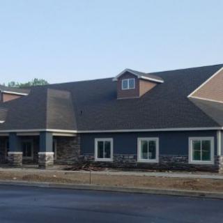 A modern residential building with a sloped roof and multiple windows on a clear day.