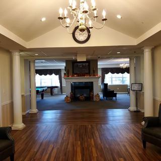 A spacious living room with a chandelier, fireplace, and wood flooring.