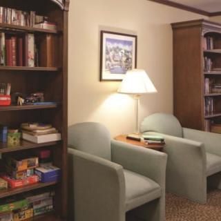 A cozy reading nook with bookshelves, chairs, and a lamp.