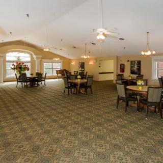 A spacious lobby area with tables and chairs, featuring large windows and decorative lighting.
