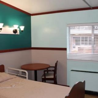 A simple hotel room with a bed, table, and chairs next to a window.