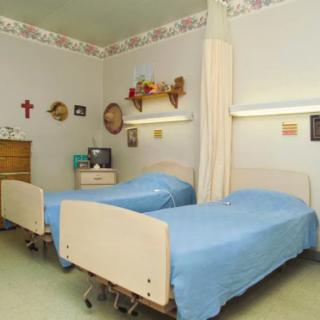 A hospital room with two twin beds separated by a curtain divider.