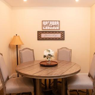 A cozy dining room with a round wooden table, surrounded by four chairs and decorated with wall art.