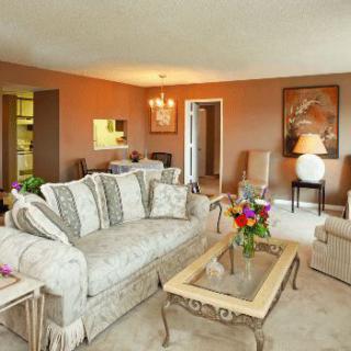 A cozy living room with a patterned sofa, wooden coffee table, and decorative elements like flowers and a painting.