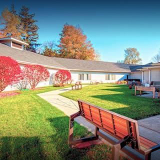 A serene garden area with benches and walkways, surrounded by autumn foliage.