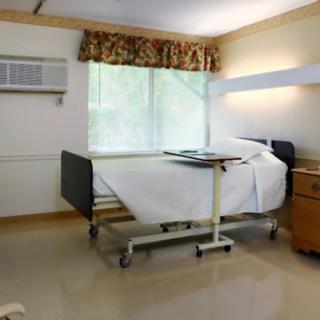 An empty hospital room with a patient bed and a window.