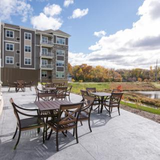 A serene outdoor patio area with tables and chairs, set against a beautiful backdrop of autumn foliage and a clear sky.