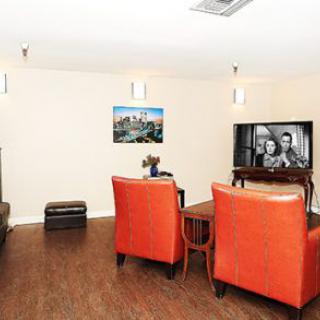 A modern living room with orange chairs, a television, and wood flooring.