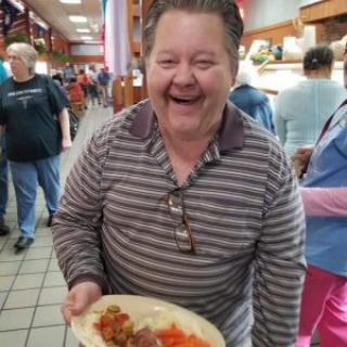 A cheerful man enjoying his meal in a bustling buffet.