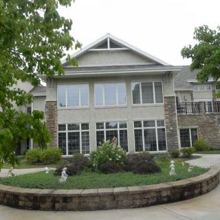 A two-story residential building with large windows and landscaping in front.
