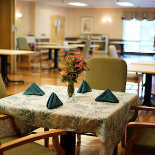 A neatly arranged dining table with a floral centerpiece in a communal dining area.