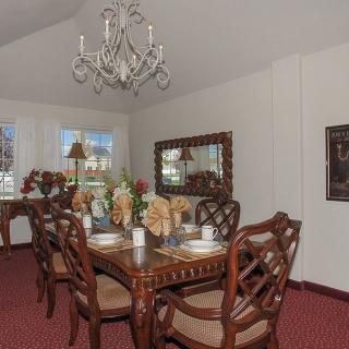 A traditional dining room with elegant table settings, a decorative chandelier, and a large mirror on the wall.