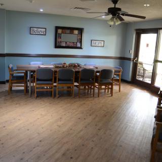 A spacious dining room featuring a long wooden table surrounded by chairs, complemented by light blue walls and ample natural light.