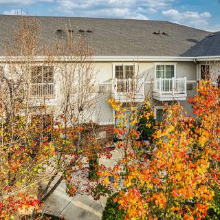 A view of a building with balconies surrounded by trees in autumn foliage.